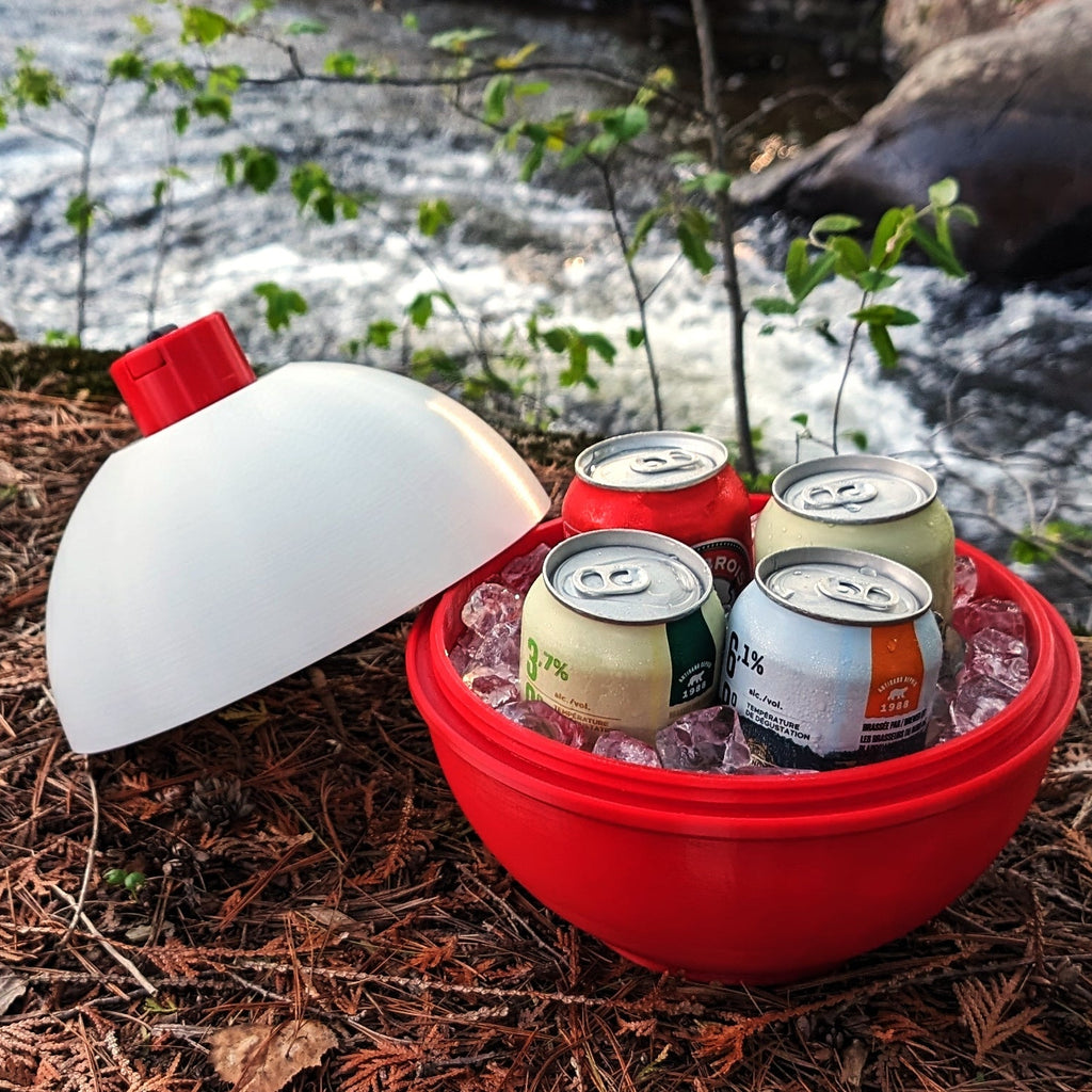 Red cooler with ice and cans by a stream