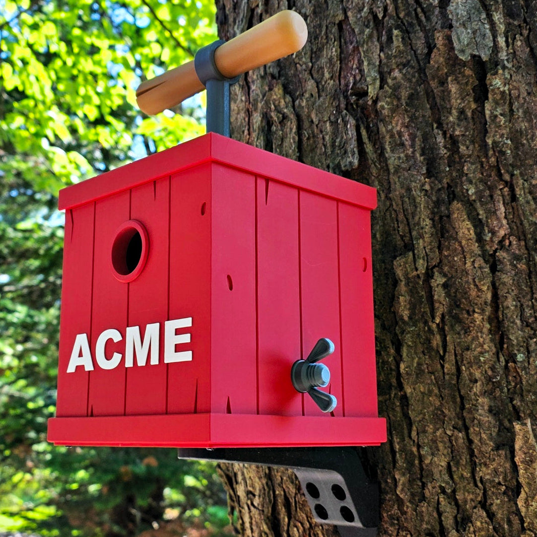 A red wooden birdhouse with 'ACME' printed in white on the front, mounted on a tree trunk outdoors. 