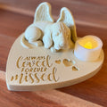 Memorial ornament with Basset Hound with Angel Wings figurine and a candle on a wooden surface