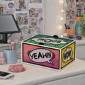 Colorful box with comic-style text bubbles on a desk with stationery items.