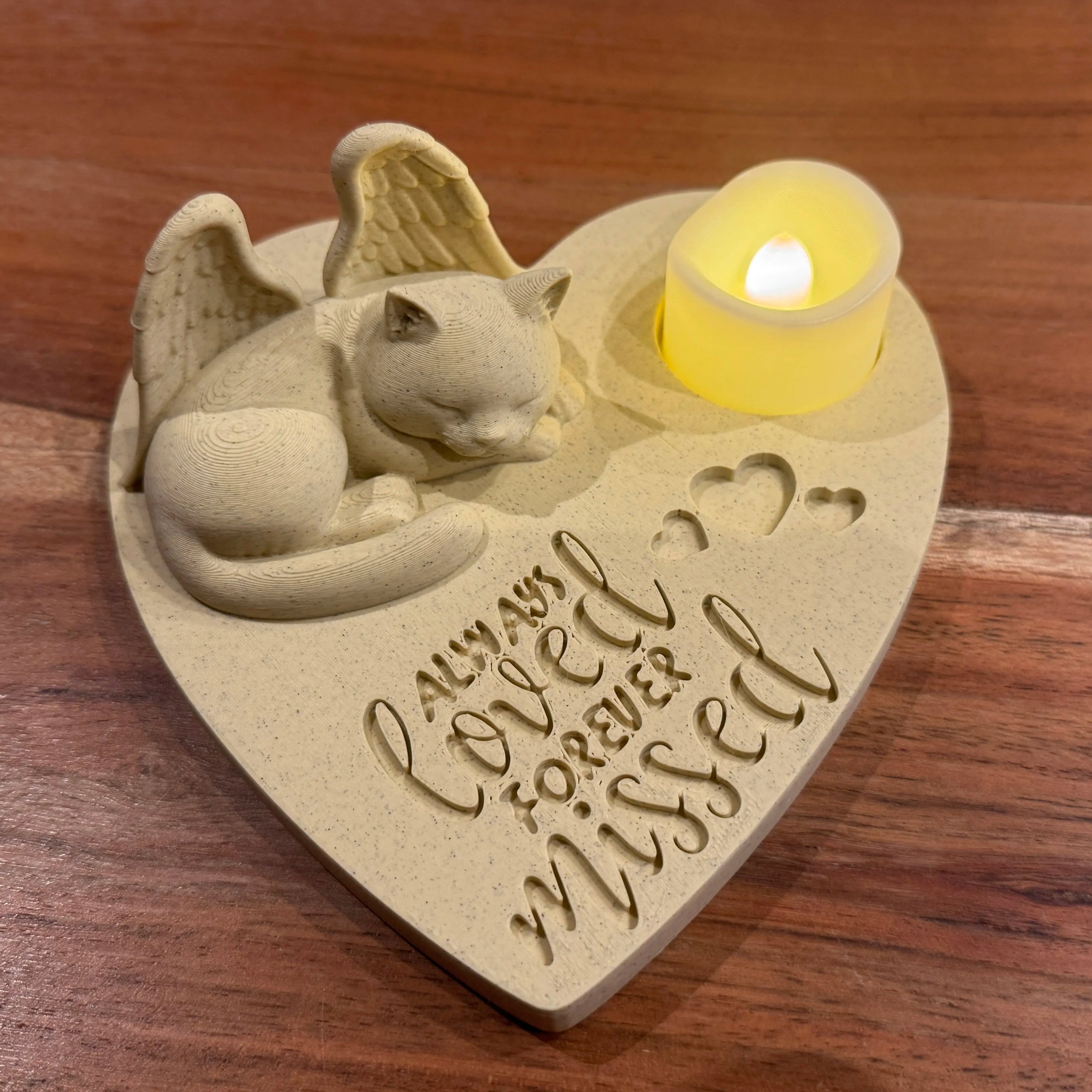 Heart-shaped memorial featuring a British shorthair cat with Angel wings and engraved text on a wooden surface