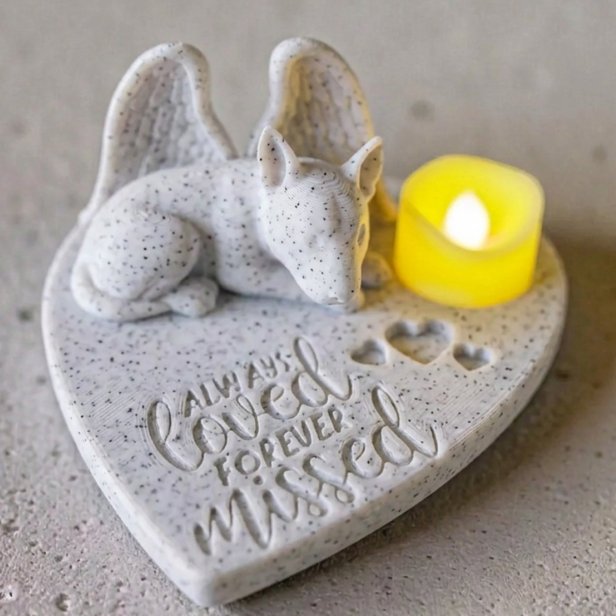 heart shaped memorial featuring a bull terrier with Angel wings and a lit candle on a gray surface.