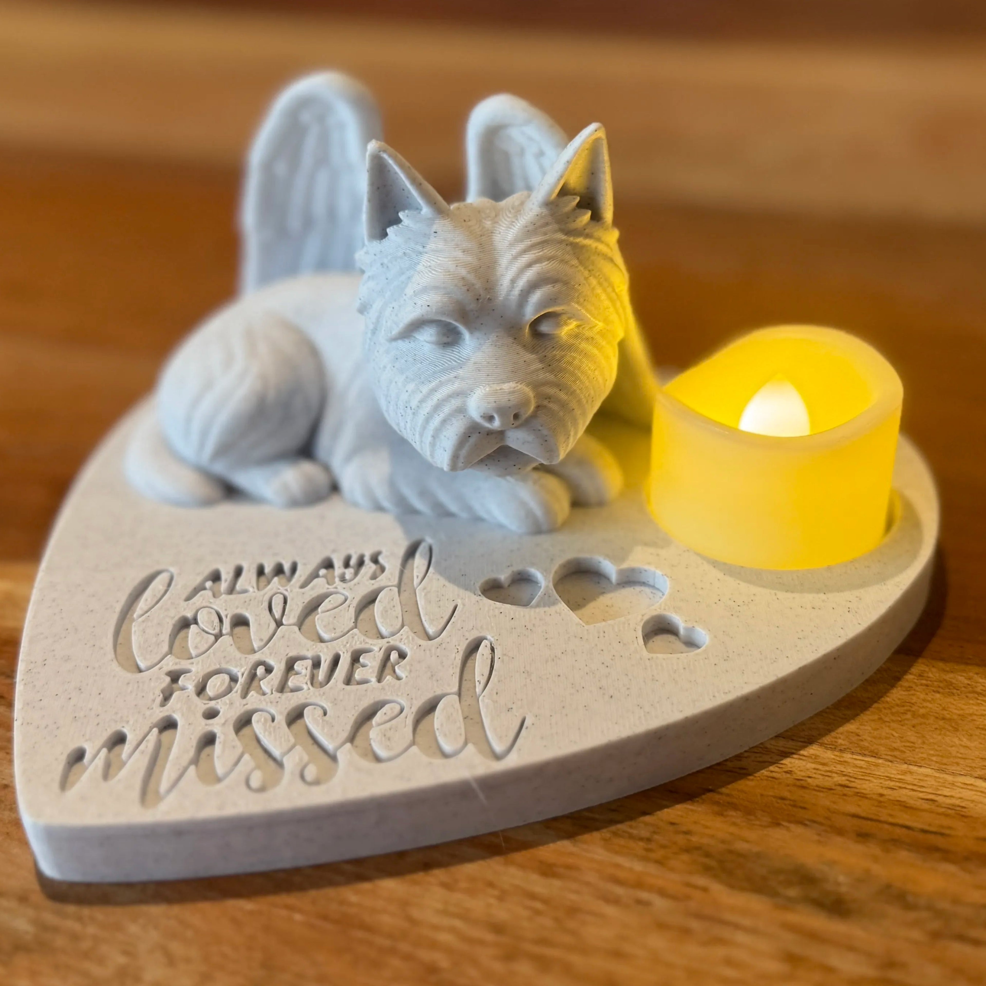 Heart-shaped plaque with a Cairn or Westy Terrier with Angel wings and candle on a wooden surface