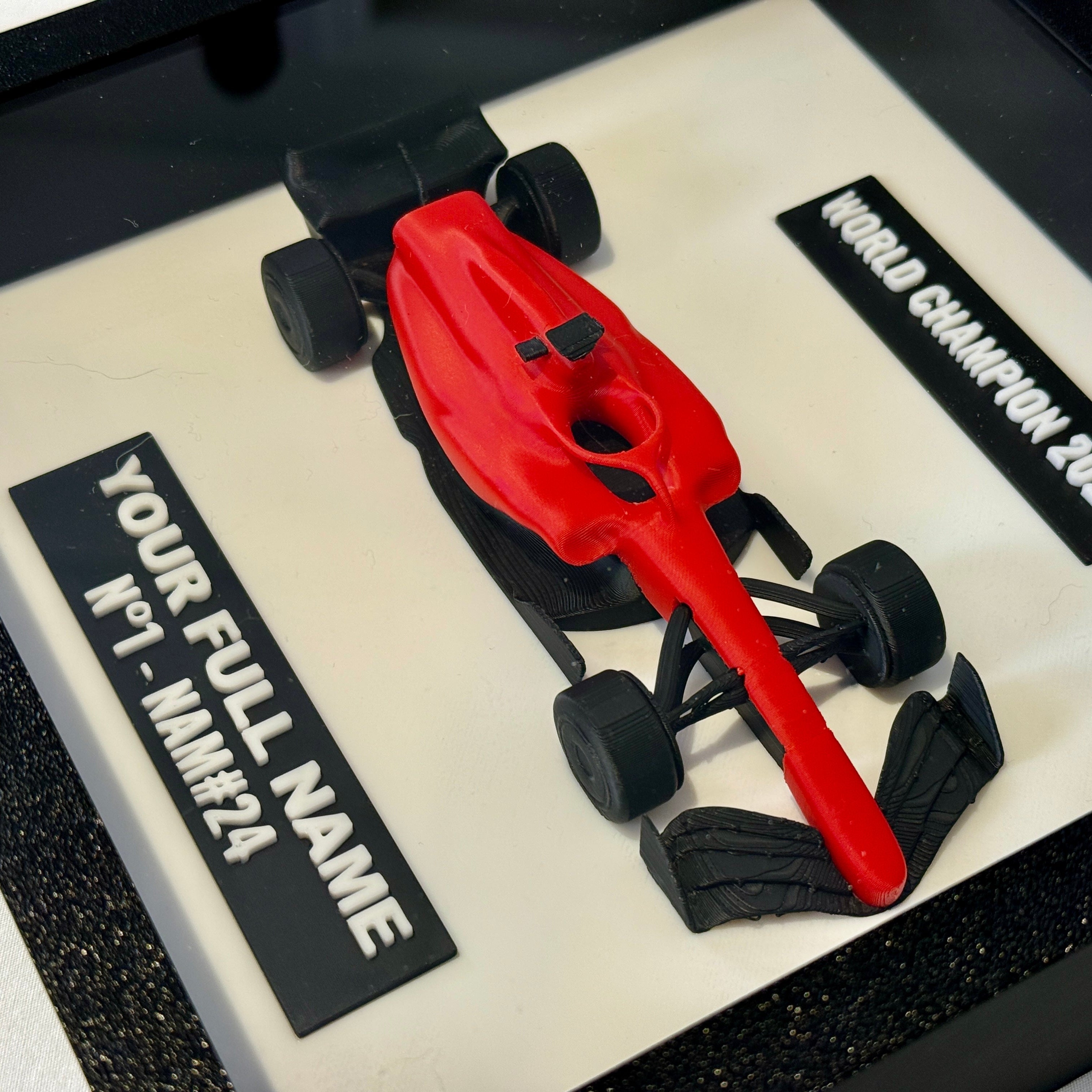 Red and black Formula 1 car model on a display stand with customizable text
