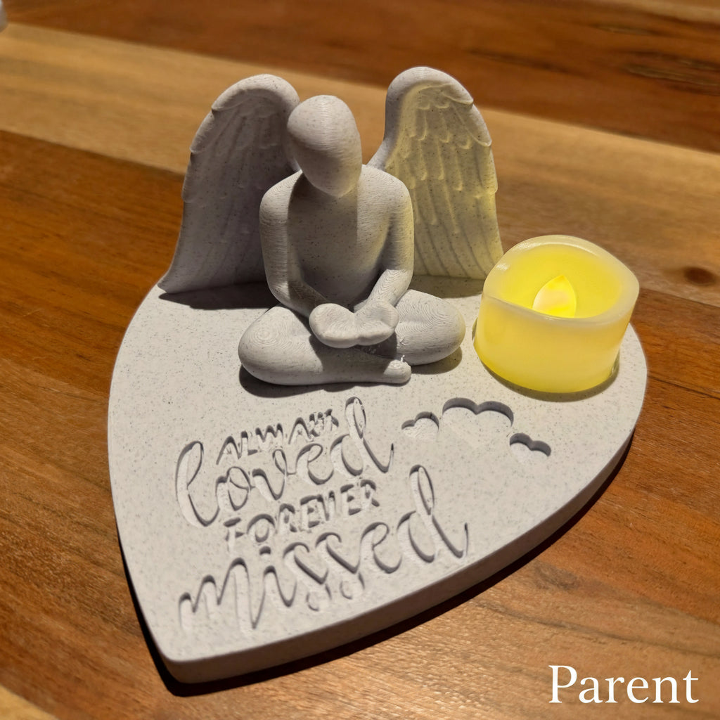 Memorial plaque with adult angel figure and candle on a marble surface