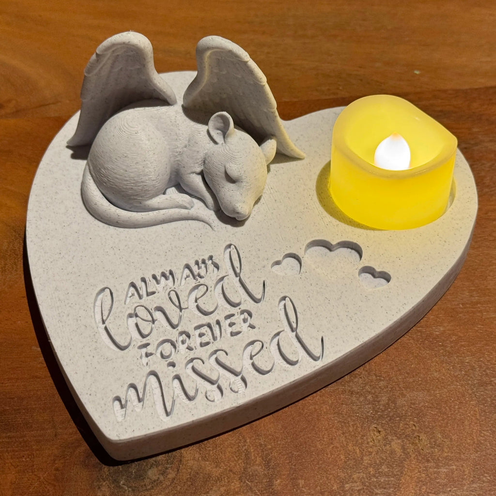 Memorial plaque with a rat with Angel wings figure and 'always loved, forever missed' text on a wooden surface.