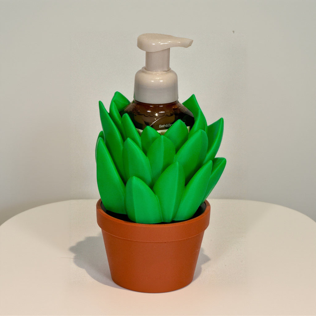Foam hand soap dispenser shaped like a green plant in a pot on a white background