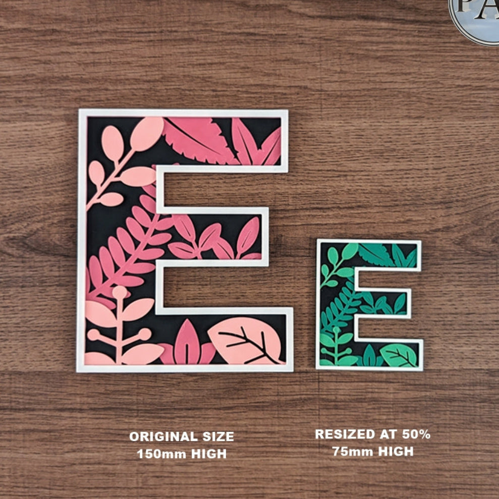 Letter 'E' with floral designs on a wooden background, showing original and resized sizes.