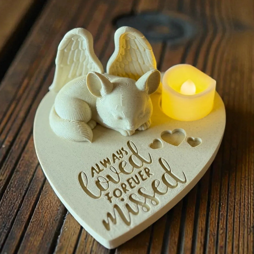 Heart-shaped memorial plaque with a small animal figurine and candle on a wooden surface