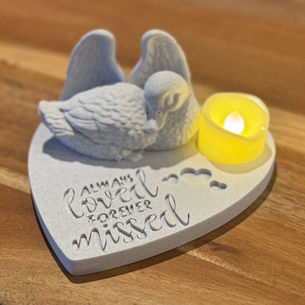 Decorative heart-shaped ornament with a duck with Angel wings and a candle on a wooden surface