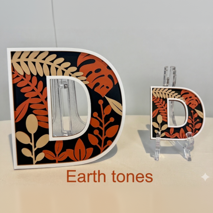 Decorative letter 'D' with leaf pattern on a stand against a neutral background