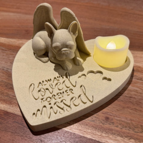Heart-shaped memorial with a French bulldog with Angel wings and candle on a wooden surface