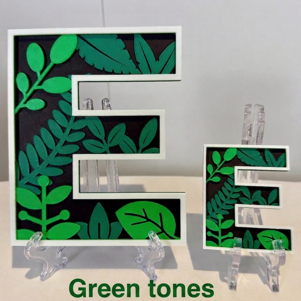 Decorative letter 'E' with green leaf pattern on a stand against a neutral background
