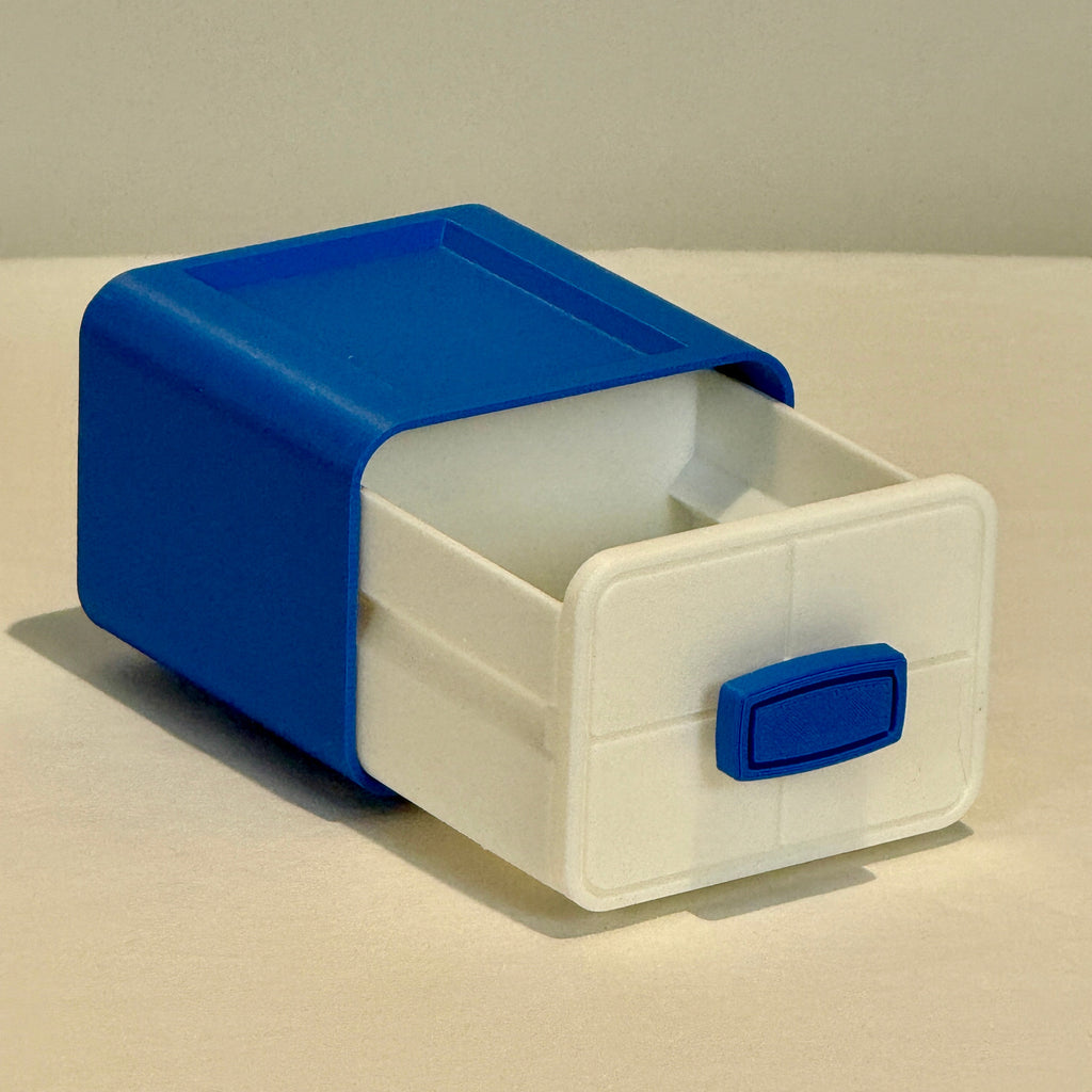 Small storage box with a blue lid and handle on a beige surface