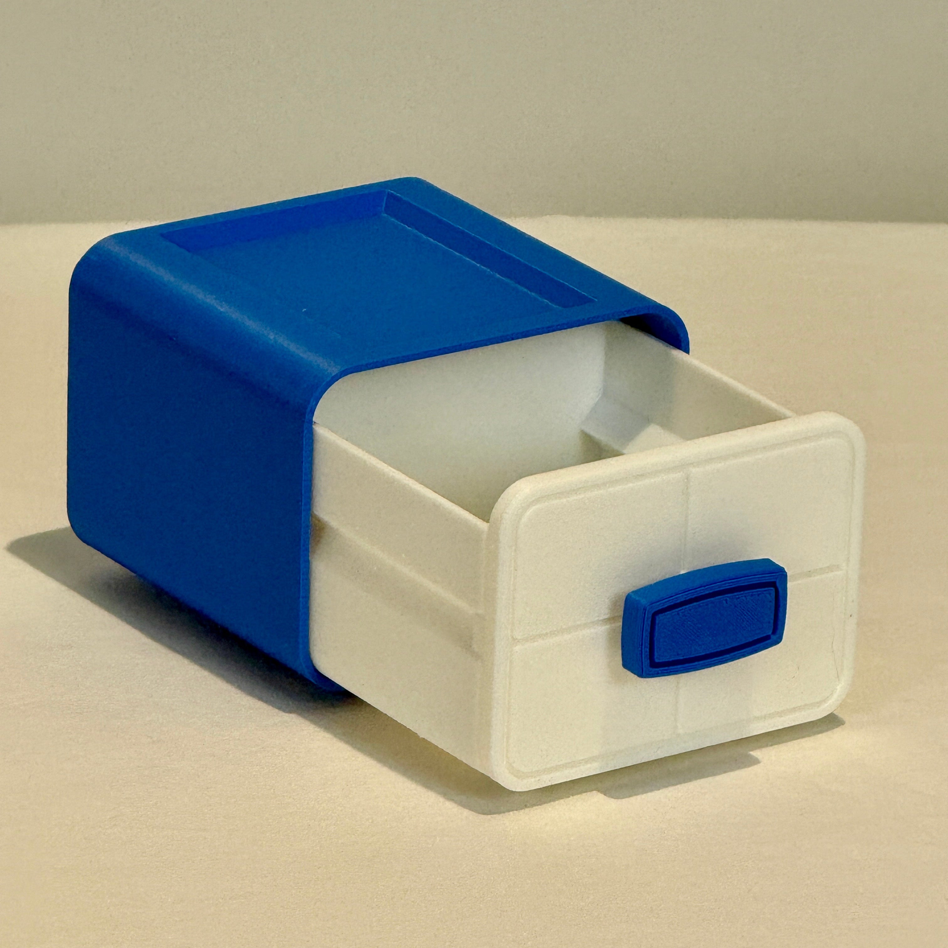 Small storage box with a blue lid and handle on a beige surface