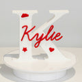 Decorative wall piece with 'Kylie' in red on a white background