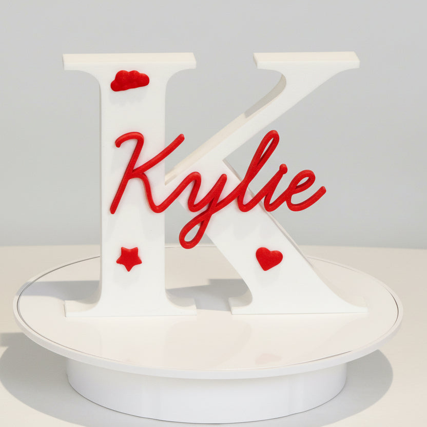 Decorative wall piece with 'Kylie' in red on a white background