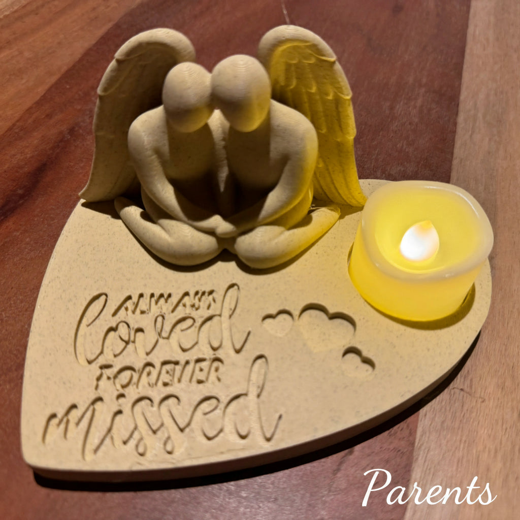 Memorial sculpture of an to people as an angel with a candle on a wooden surface