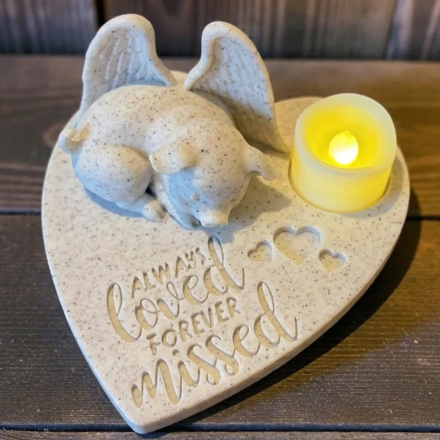 Heart-shaped memorial witpig with Angel wings figurine and 'Always Loved Forever Missed' text, illuminated by a small candle.