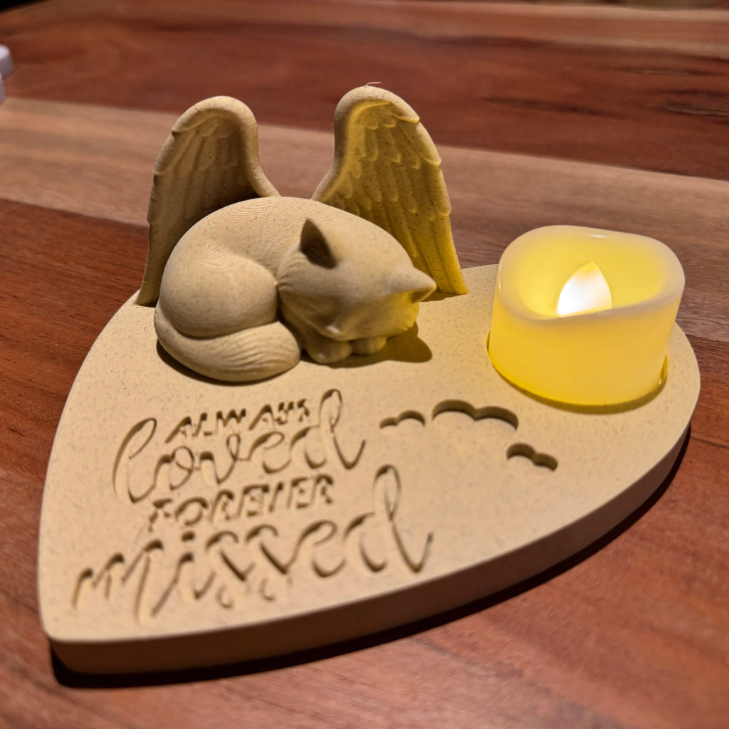 Memorial sculpture of a ragdoll cat with Angel wings and a candle on a wooden base, featuring the text 'Always Loved Forever Missed'.