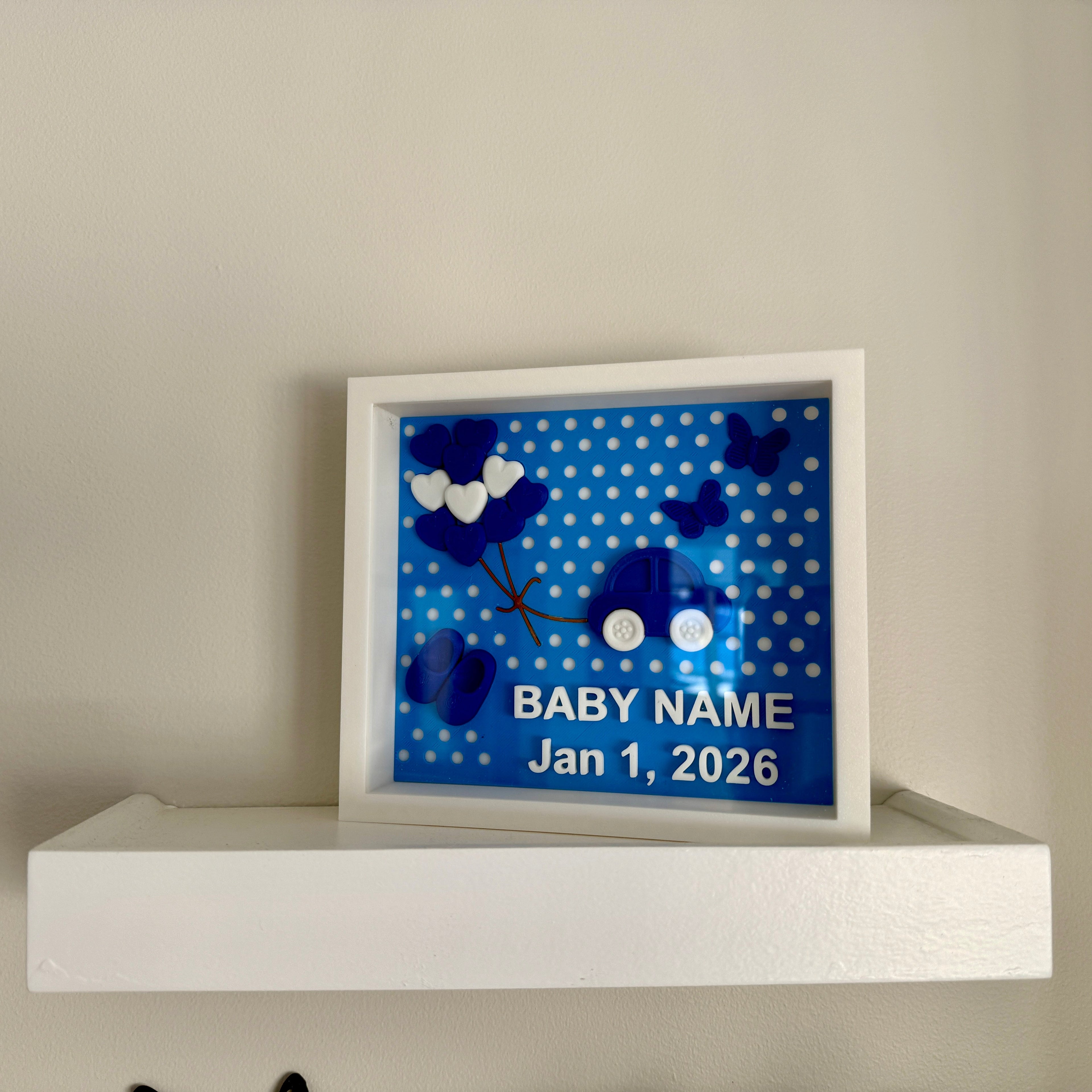 Decorative shadow box with blue polka dot design and text placeholder on a white shelf.