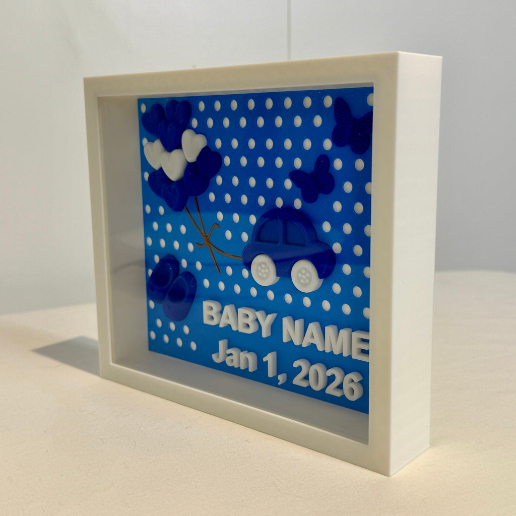 Decorative baby shadow box with blue polka dots and car design on a white background
