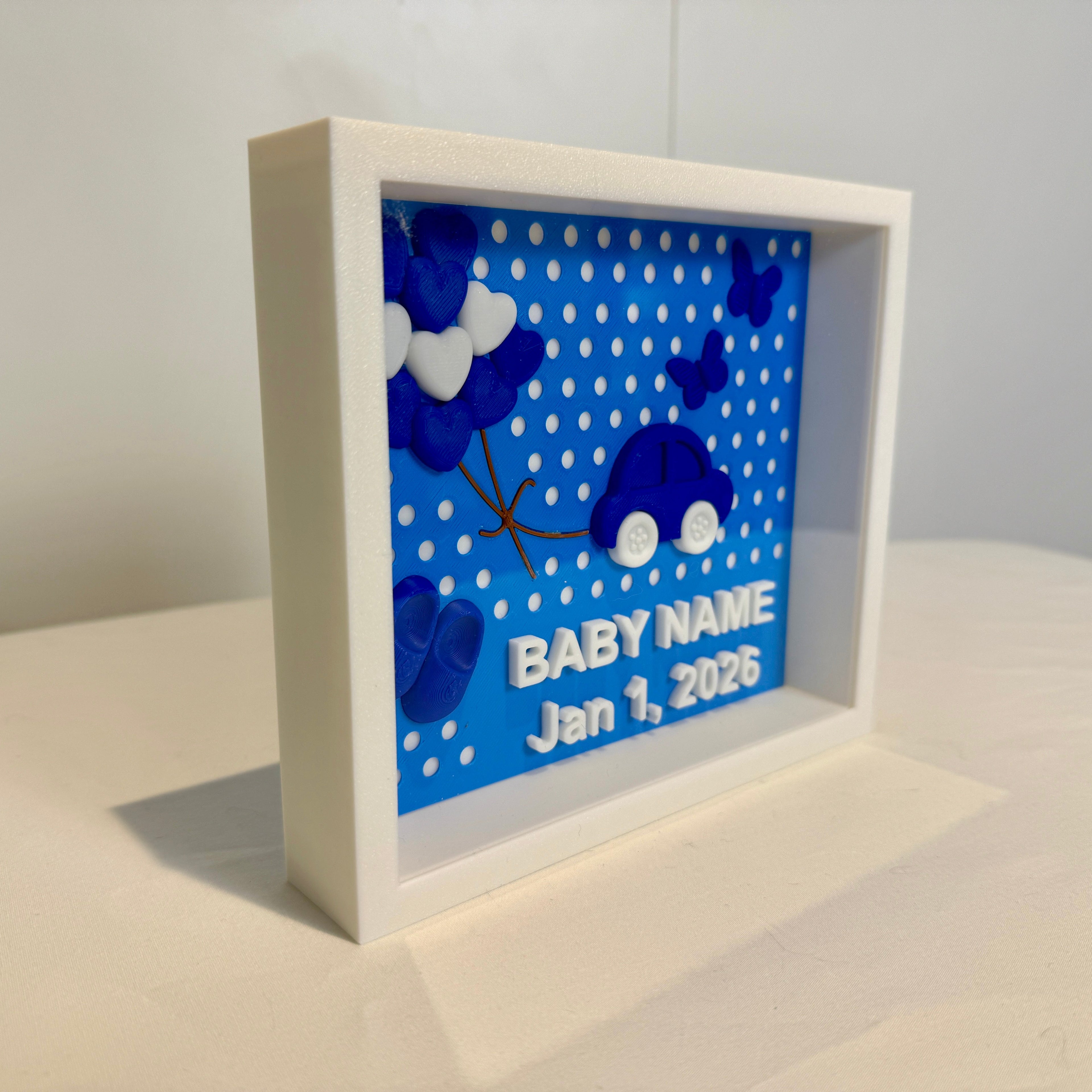 White shadow box with blue polka dot background and baby-themed design on a white surface.