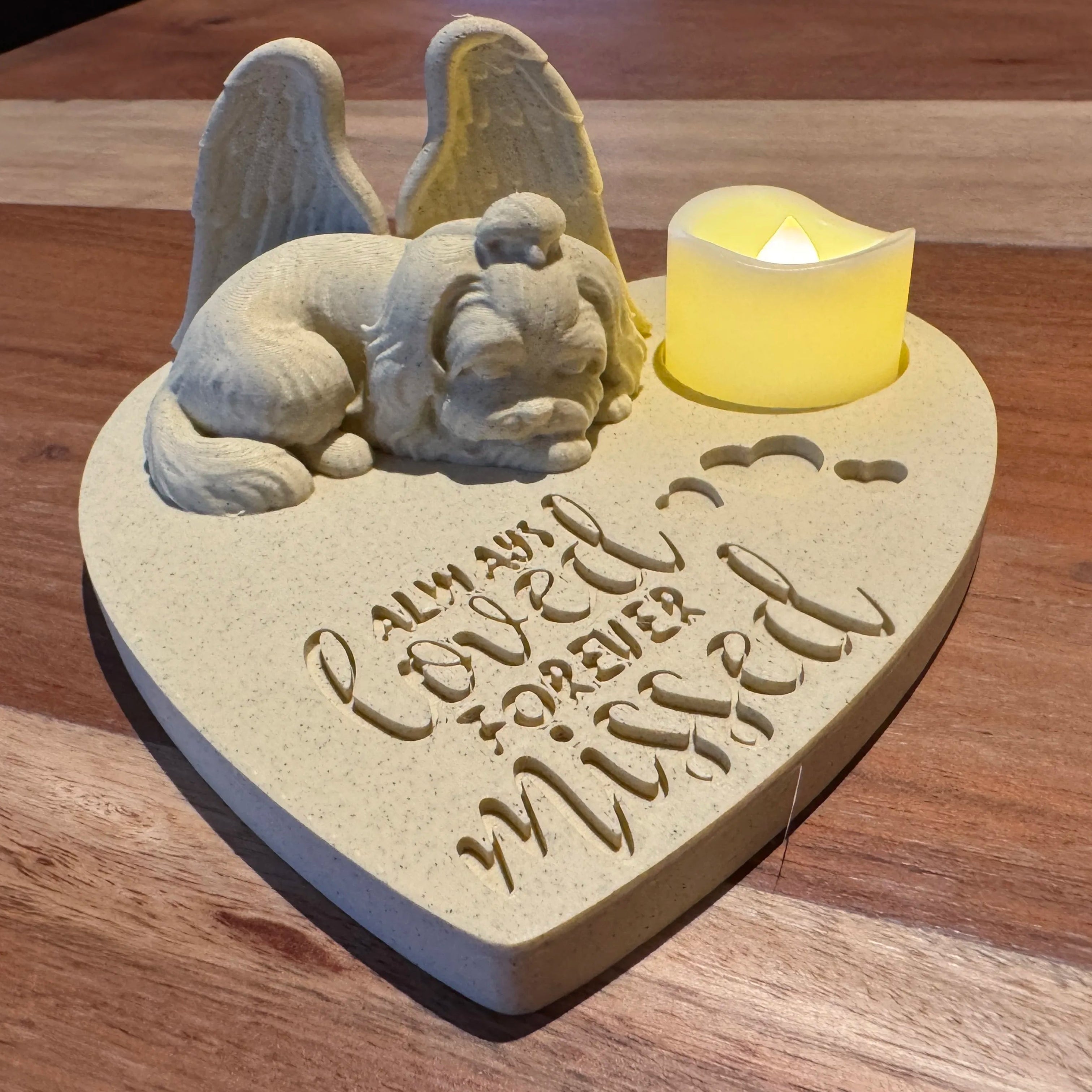 Heart-shaped memorial with a Schnauzer or Lhasa Apso with Angel wings figurine and candle on a wooden surface