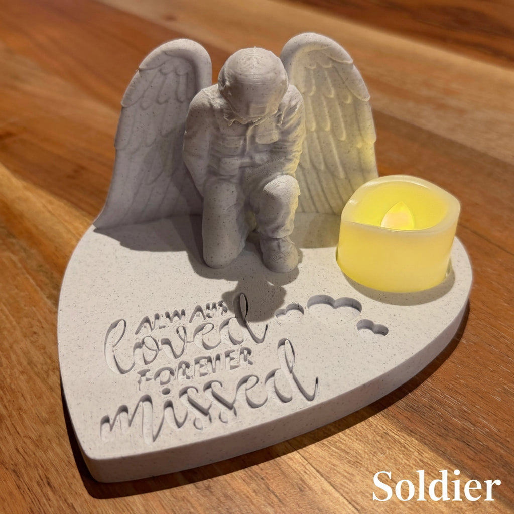 Memorial sculpture of an angel soldier with a candle on a wooden surface