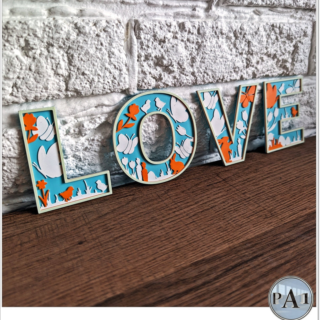 Decorative letters spelling 'LOVE' with a floral pattern on a wooden surface.