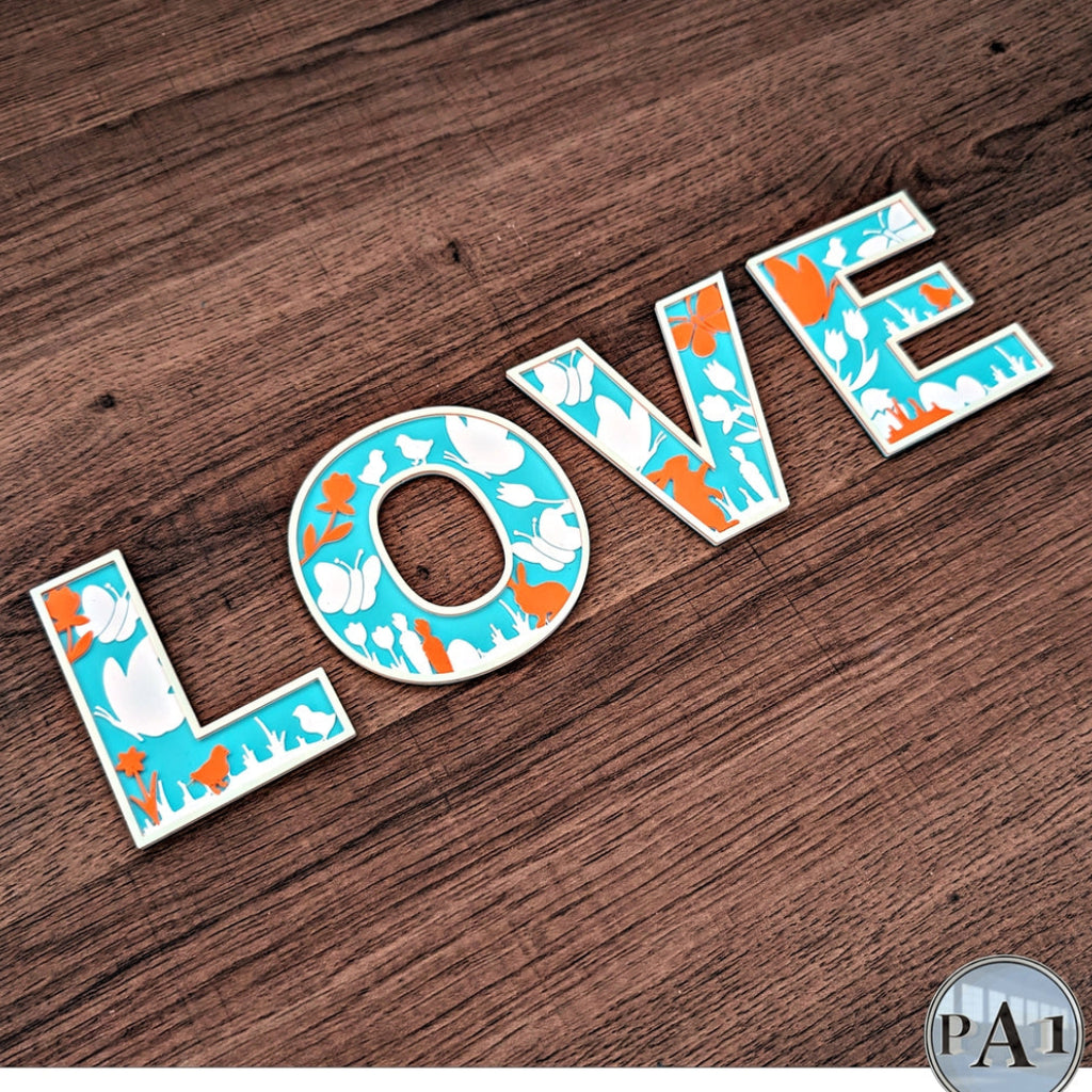 Decorative letters spelling 'LOVE' on a wooden surface with a patterned design.