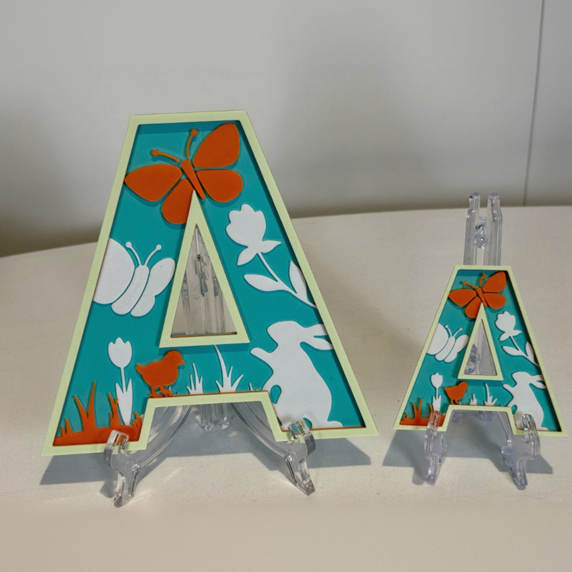 Two decorative letter 'A' with butterfly, rabbit, and flower designs on a white background.
