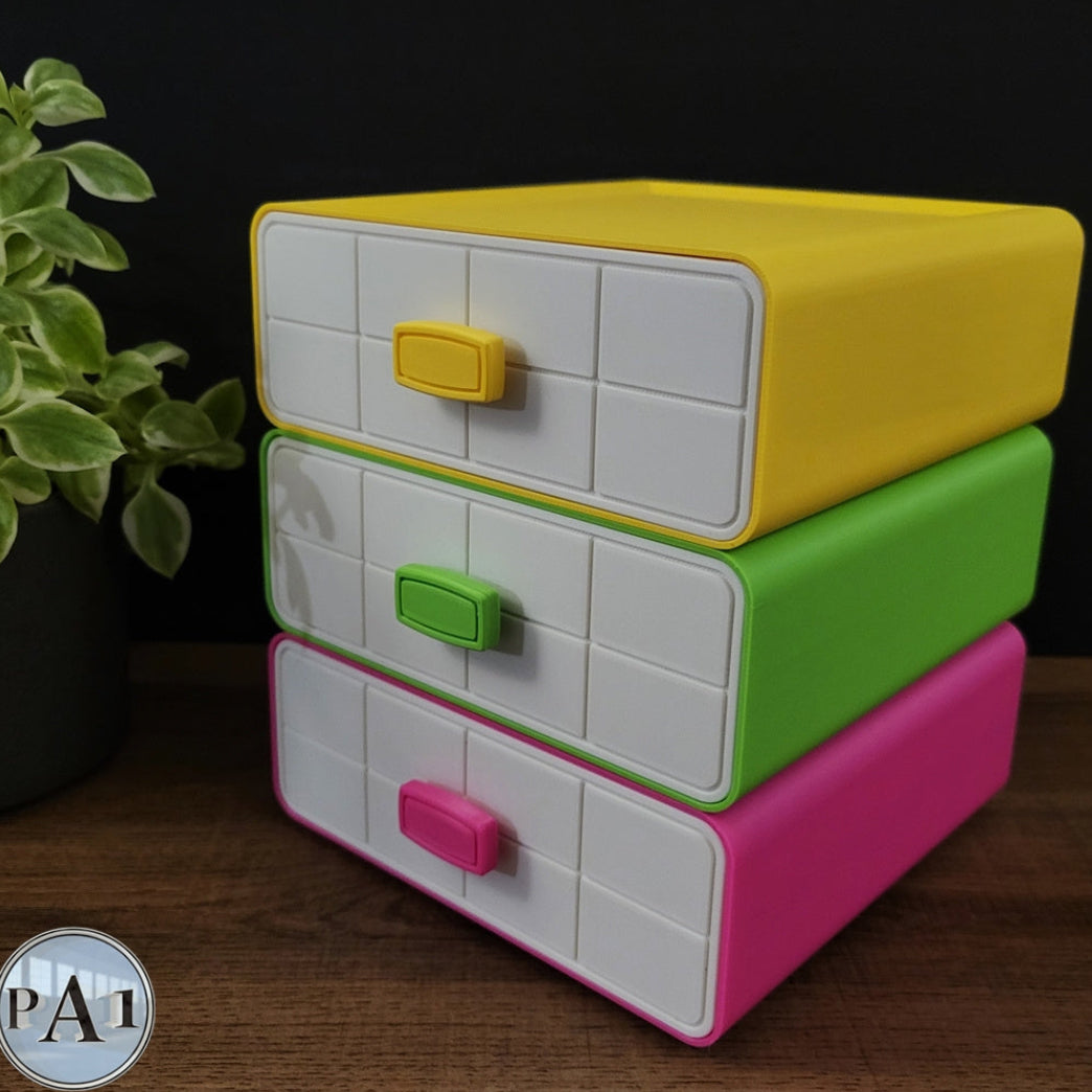 Stack of colorful plastic drawers with tiled fronts on a wooden surface.