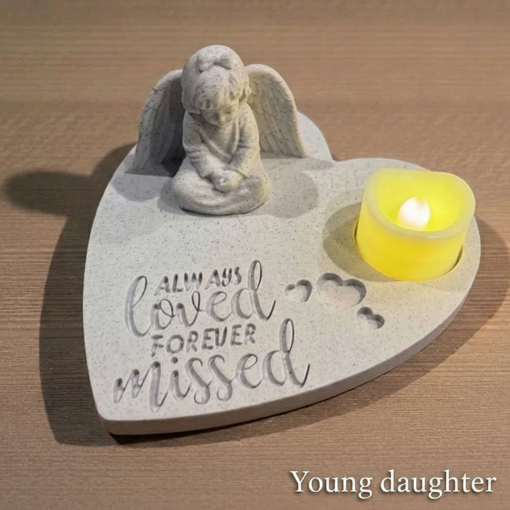 Memorial plaque with young daughter angel figure and candle on a wooden surface
