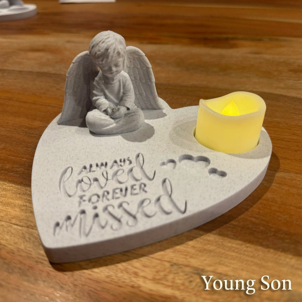 Memorial figurine of young boy with angel wings and candle on a marble surface